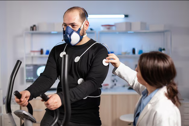 A female doctor is placing trackers on a man's arms for a cardiac rehab session.